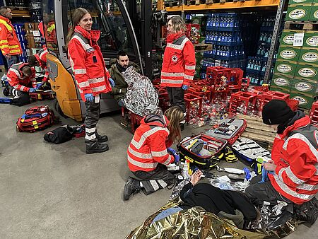 Einsatzkräfte sin in einer Lagerhalle an Patienten und versorgen diese. 